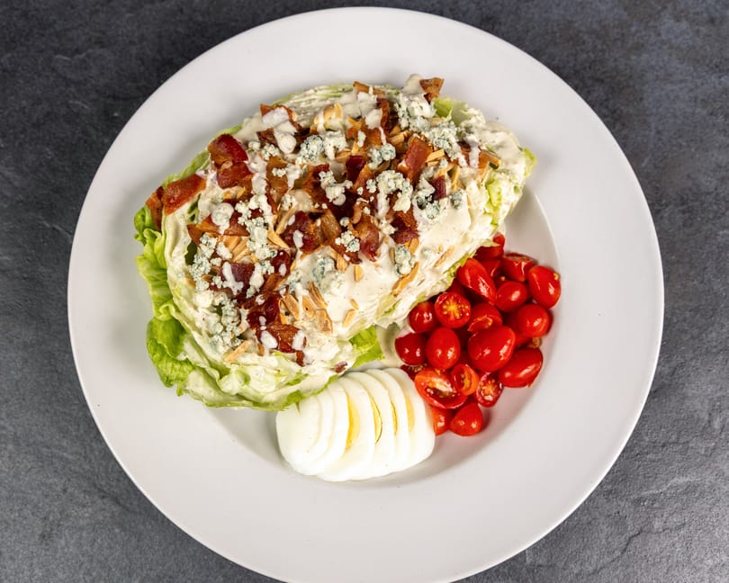 Wedge salad with blue cheese, bacon, almonds, cherry tomatoes, and sliced hard-boiled egg.